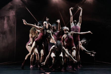 Acosta Danza dancers in burgundy costumes reach and lean as an ensemble in Andonis Foniadakis’s Pearls at Sadler’s Wells