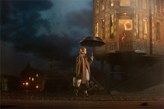 A woman with an umbrella on the dark street outside the Birling house in An Inspector Calls, 2024 UK touring company. Photo by Mark Douet