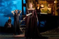 A woman in a burgundy evening gown with members of the company in An Inspector Calls, 2024 UK touring company. Photo by Mark Douet