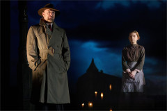 The Inspector, in trench coat and hat, beside a young woman in a maid's uniform in An Inspector Calls, 2024 UK touring company. Photo by Mark Douet