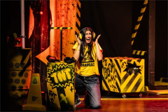 A Brainiac in ear defenders beside a TNT crate in Brainiac Live. Photo by Danny Kaan