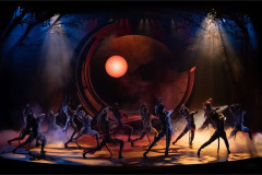 The Cats company dancing in front of a glowing orange moon. Photo by Mark Senior