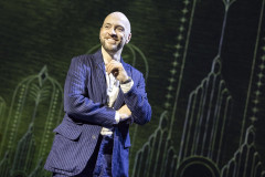 Derren Brown in a pinstripe suit, smiling, on stage in Only Human at the Apollo Theatre