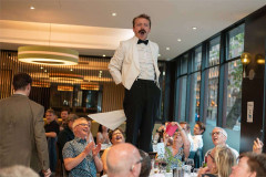 Manuel stands on a chair to address the room at Faulty Towers The Dining Experience. Photo by That’s Up