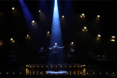 A performer sings in a single blue spotlight in From The Heart. Photo by Eamonn B Shanahan