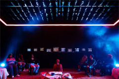 The cast of Girls beneath a row of television screens. Photo by Helen Murray