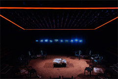 Raphaé Memon's set for Girls, with red sand and a row of television screens. Photo by Helen Murray