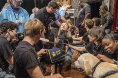 A black Labrador puppy reaches up to greet a member of the cast as the company gathers round. Photo by Ellie Kurttz