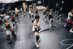 The company of The Hunger Games: On Stage rehearsing with staffs. Photo by Danny Kaan