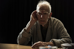 Peter Marinker as Krapp, a hand cupped to his ear at his desk, in Krapp’s Last Tape at The Cockpit