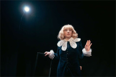 Jordana Belaiche as Little Lord Fondleroy, standing under a spotlight with one hand raised