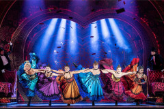 The company in a line of colourful skirts under blue light in Moulin Rouge! The Musical. Photo by Johan Persson The company in a line of colourful skirts under blue light in Moulin Rouge! The Musical. Photo by Johan Persson