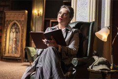 The detective of Murder, She Didn't Write in a library armchair with an open notebook. Photo by Pamela Raith