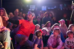 Baffo crouches in front of a young audience in On Your Bike Baffo! Photo by Paul Blakemore
