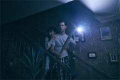 Ami Okumura Jones as Lou and Ty Fanning as James on the stairs with a torch and a baseball bat in Paranormal Activity. Photo by Matt Crockett