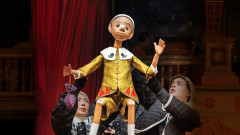 The Pinocchio puppet held aloft by its puppeteers on the Globe stage. Photo by Johan Persson