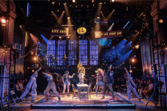 The company of Rent on stage at the Life Cafe, with Gaten Matarazzo standing on the table at the centre. Photo by Pamela Raith