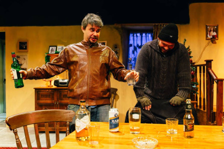 Two of the card players at the kitchen table, whiskey bottle in hand, in The Seafarer at Greenwich Theatre