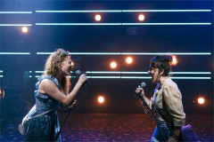 Two performers sing side by side under neon strip lights in Thelma &amp; Louise at the Young Vic. Photo by Helen Murray