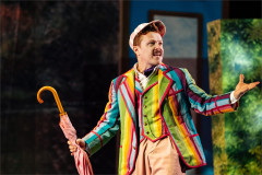 Jonny Weldon as Jerome in a striped blazer, holding a pink umbrella. Photo by Helen Murray