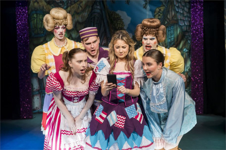The cast of Tinderella gathered around a smartphone