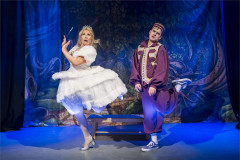 Tinderella in a white ball gown beside a prince in purple