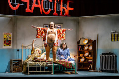 A man in a dressing gown stands on the bed in To Die For [A Comedy], Nederlandse Reisopera's 2026 Dutch touring production