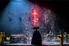 Snow falls beneath a neon cross in To Die For [A Comedy], Nederlandse Reisopera's 2026 Dutch touring production
