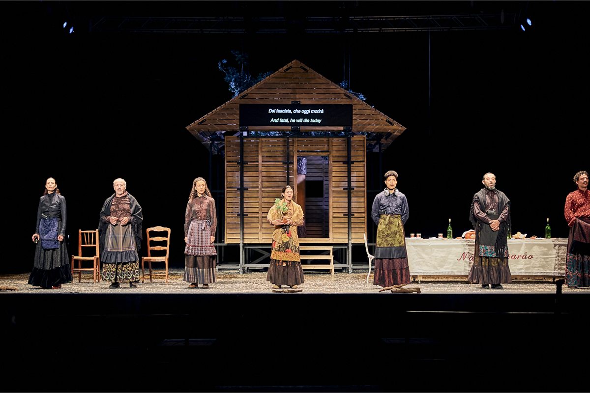 The company of Catarina and the Beauty of Killing Fascists lined up across the Dorfman stage in front of the wooden farmhouse