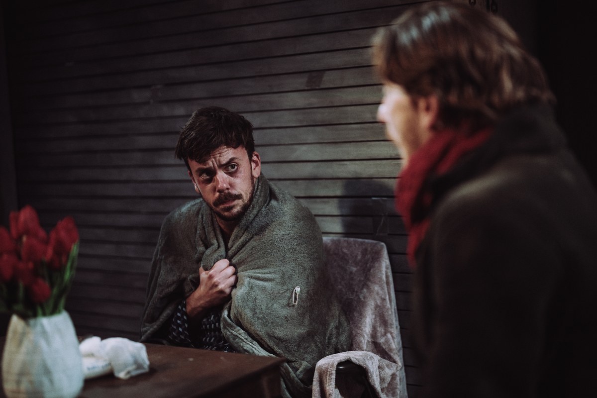 Ross Gaynor as Ashton wrapped in a blanket in A Slow Fire at Jermyn Street Theatre