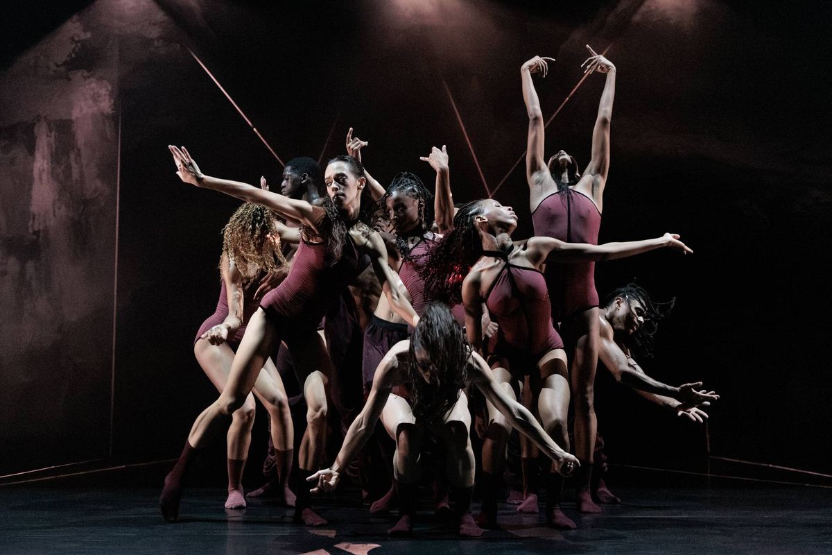 Acosta Danza dancers in burgundy costumes reach and lean as an ensemble in Andonis Foniadakis’s Pearls at Sadler’s Wells