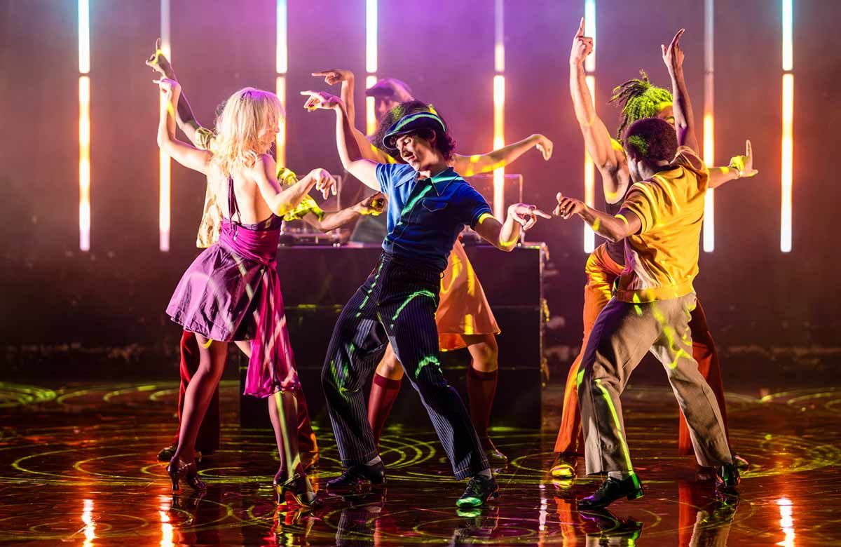 The cast of The Brown Suite dancing under neon light tubes at Richmond Theatre