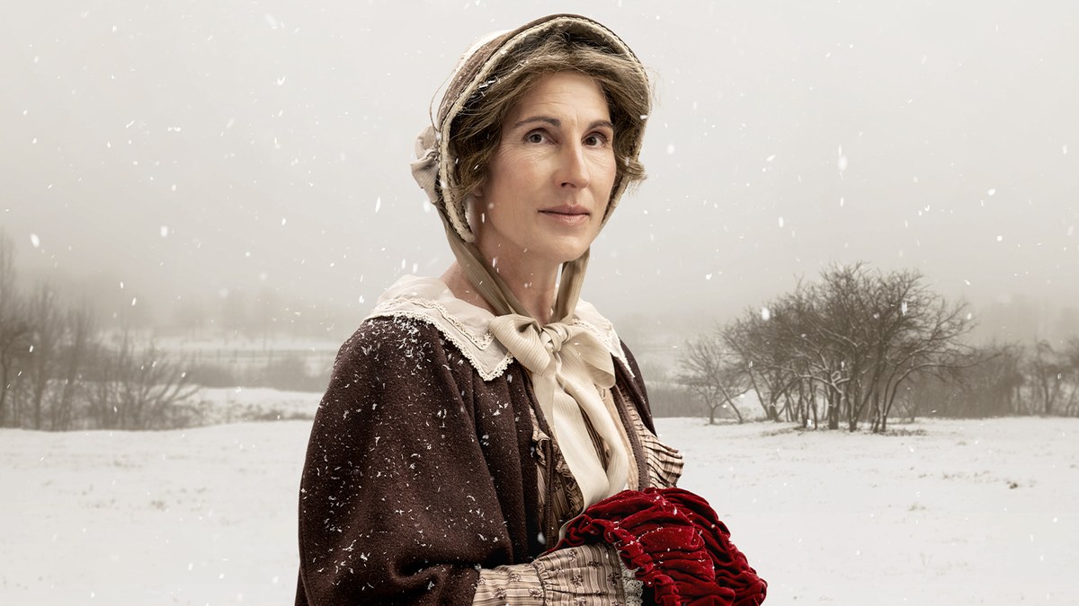Tamsin Greig as Matty Jenkyns in a bonnet and brown cloak in falling snow, production artwork for Cranford at the Orange Tree Theatre