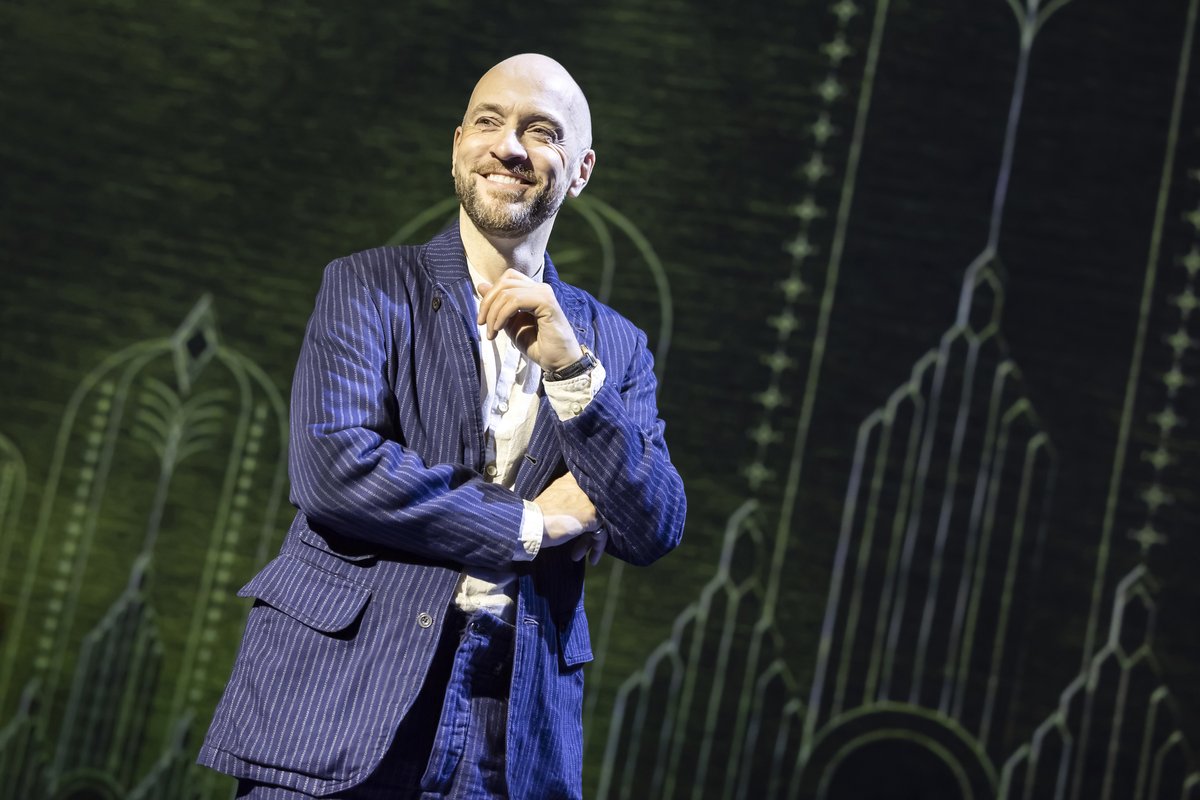 Derren Brown in a pinstripe suit, smiling, on stage in Only Human at the Apollo Theatre