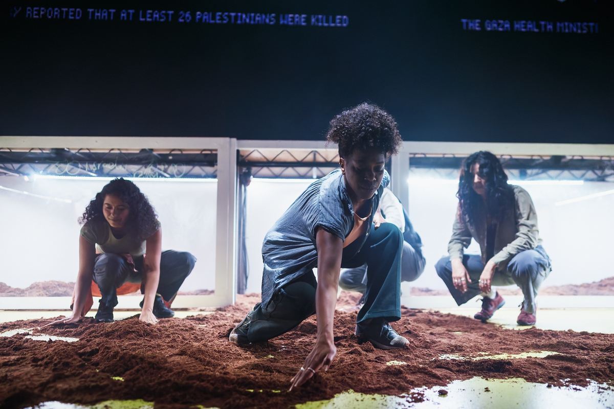 The company in the earth-covered set of The First Year (of the Gaza Genocide in the Media). Photo by Alex Brenner