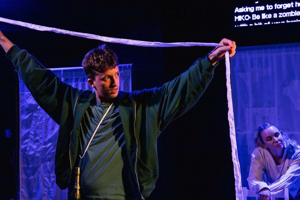 Joseph Clarke as Robbie holding a length of white cloth in Flock