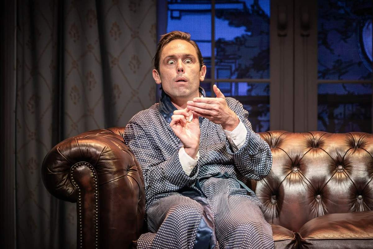 Sam Harrison seated on the Chesterfield sofa in Jeeves Takes Charge at the Charing Cross Theatre