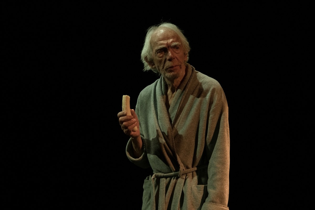 Peter Marinker as Krapp, holding a banana in the darkness, at The Cockpit