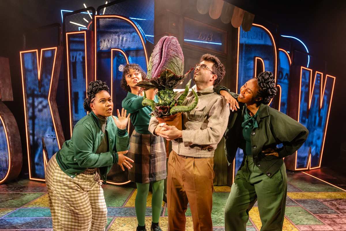 Jed Berry as Seymour with the urchins Chiffon, Crystal and Ronnette in Little Shop of Horrors at Hope Mill Theatre. Photo by Danny Kaan Jed Berry as Seymour with the urchins Chiffon, Crystal and Ronnette in Little Shop of Horrors at Hope Mill Theatre. Photo by Danny Kaan