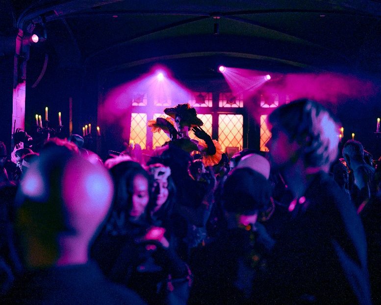 Masked guests beneath pink light at Le Bal Macabre, the Halloween ball staged by Masquerade in New York. Photo by Mark Minton