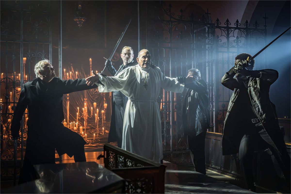 David Suchet as Thomas Becket surrounded by the four knights with raised swords in Murder in the Cathedral. Photo by Marc Brenner