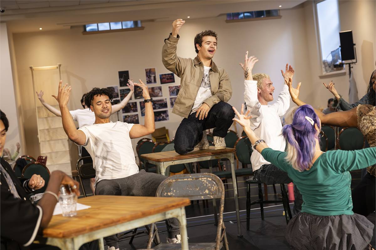 Gaten Matarazzo on a table with the company in rehearsal for Rent. Photo by Pamela Raith