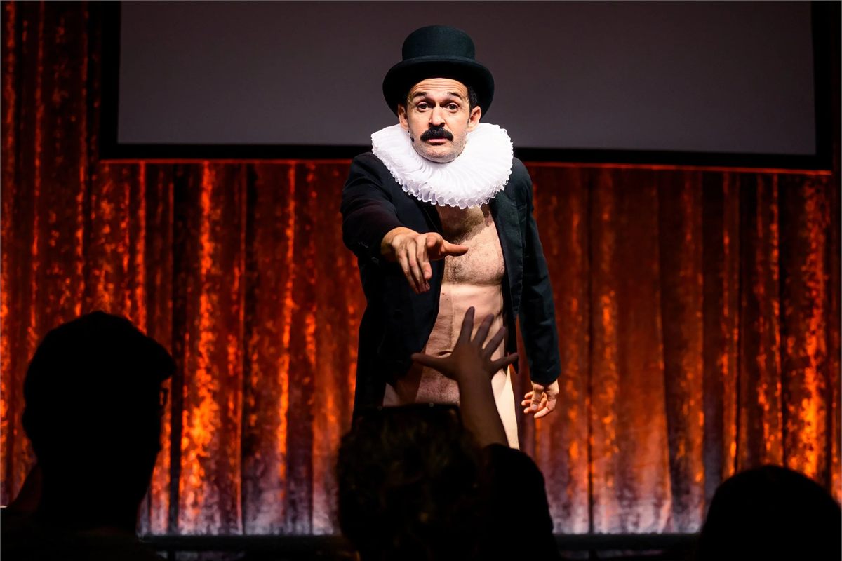 Damien Warren-Smith as Garry Starr, in a top hat and ruff, pointing into the audience in Garry Starr: Classic Penguins