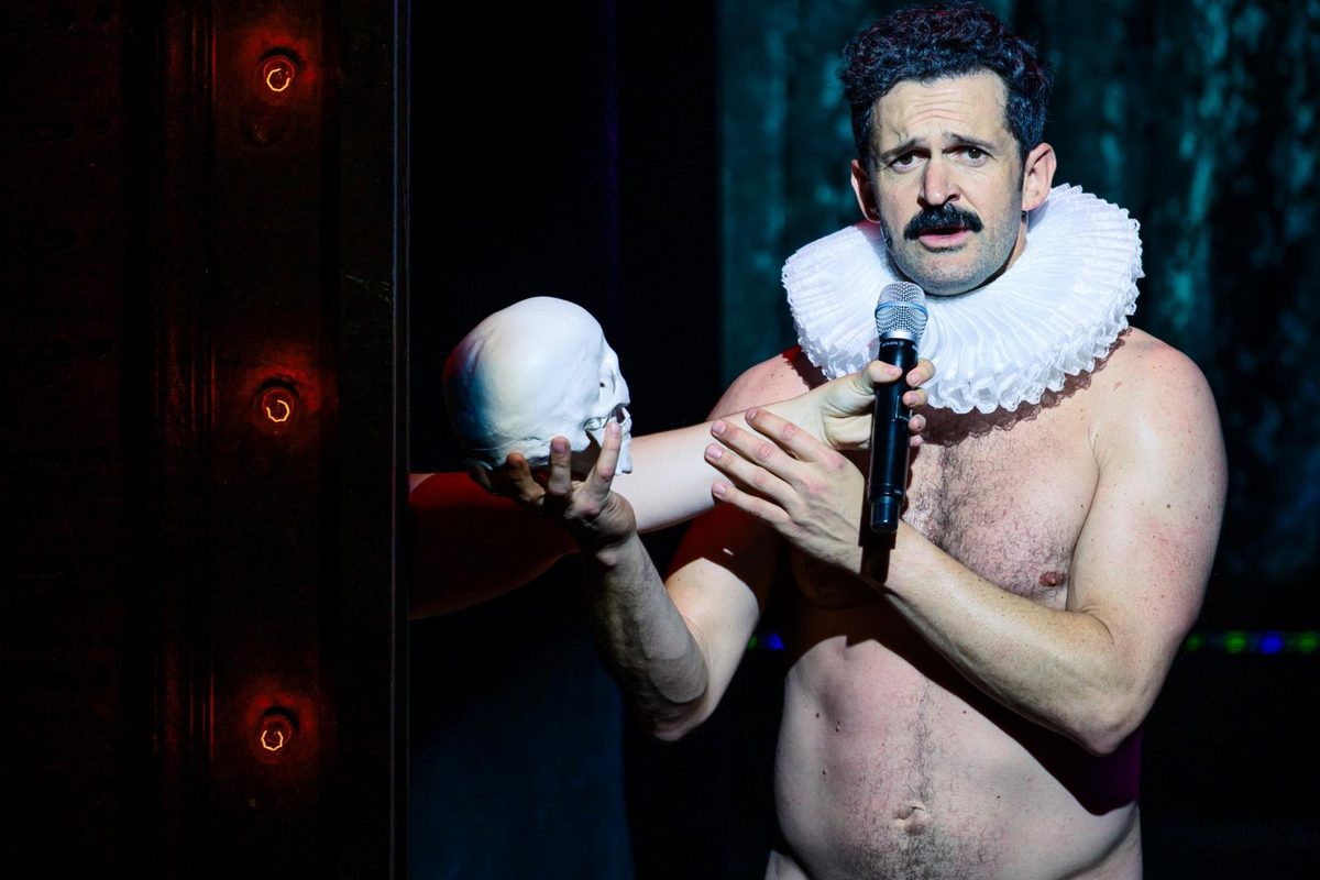 Damien Warren-Smith as Garry Starr holding a skull and a microphone in Garry Starr: Classic Penguins