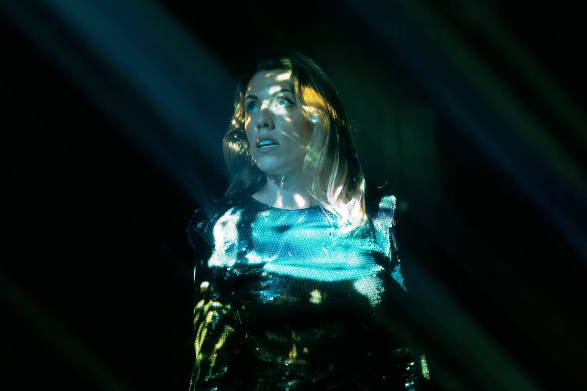 Hannah Reilly in a sequinned top looks up through shafts of green light in Roleplay Hannah Reilly in a sequinned top looks up through shafts of green light in Roleplay