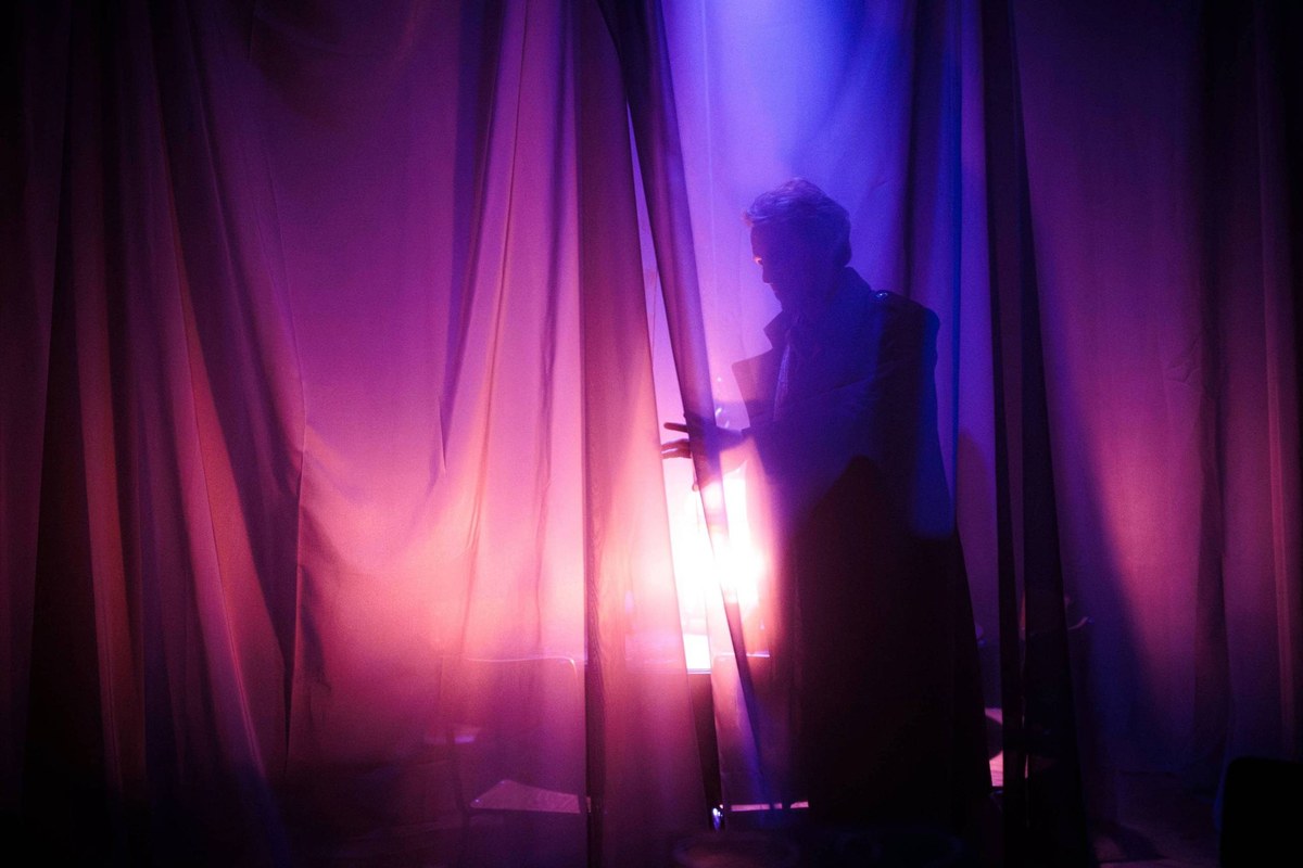 A shadowy figure parts glowing purple curtains in Room 13 at Battersea Arts Centre A shadowy figure parts glowing purple curtains in Room 13 at Battersea Arts Centre
