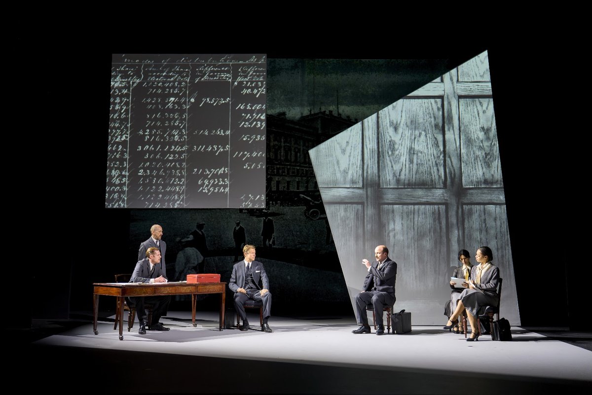 A Treasury scene from The Standard of Living, with ledgers projected on Bob Crowley’s set. Photo by Manuel Harlan