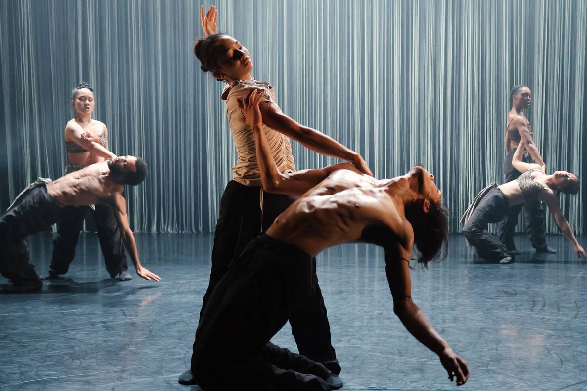 A dancer leans over a partner arched backwards in front of a curtain of strings in Tellus by Dickson Mbi Company