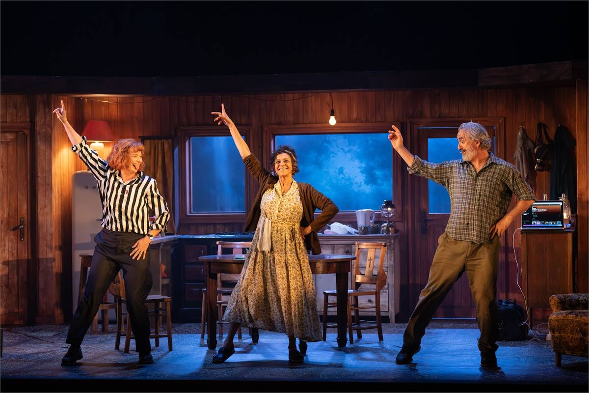 Three actors dancing in a wood-panelled seaside cottage in The Children at the Lyric Hammersmith. Photo by Helen Maybanks