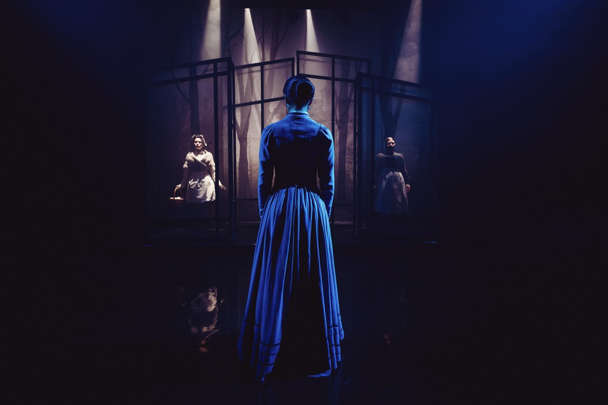 The Governess before the lit screens of Bly in The Turn of the Screw at the Arcola Theatre